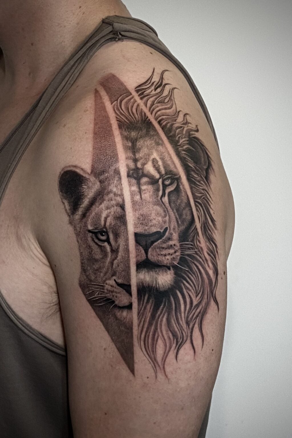 Lion tattoo on person's upper arm, featuring detailed mane and face.