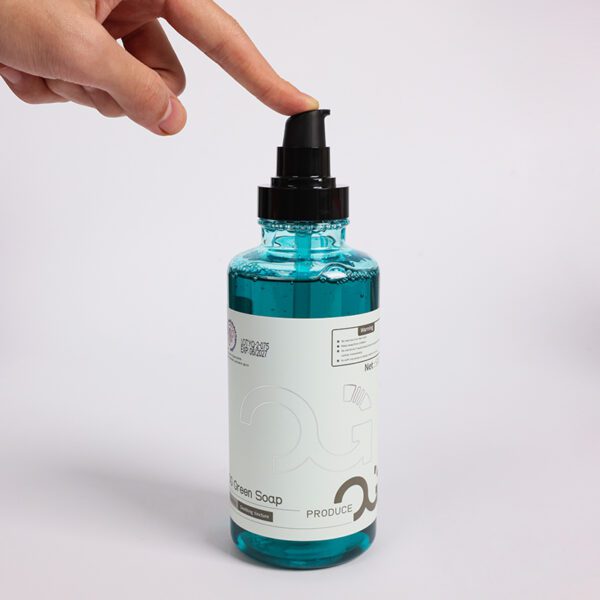 Finger pressing pump on a bottle of green soap.