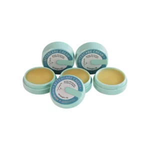 Five open containers of aftercare cream with blue lids.