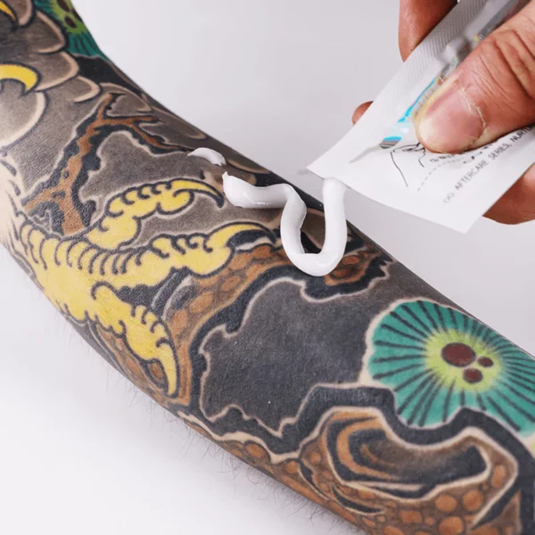 Applying ointment to a colorful tattooed arm.